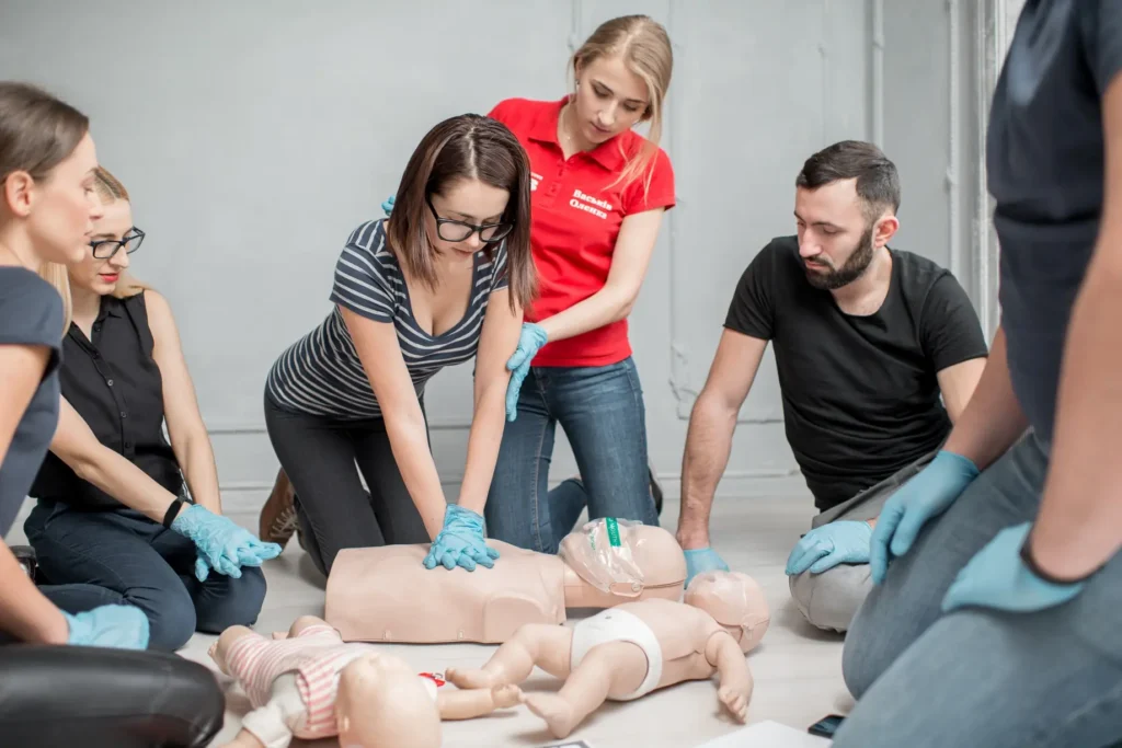 Participant performing CPR on adult manikin during certified first aid course